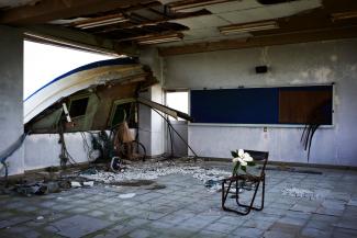 Flower on a chair in an empty room, a wrecked boat resting in the window